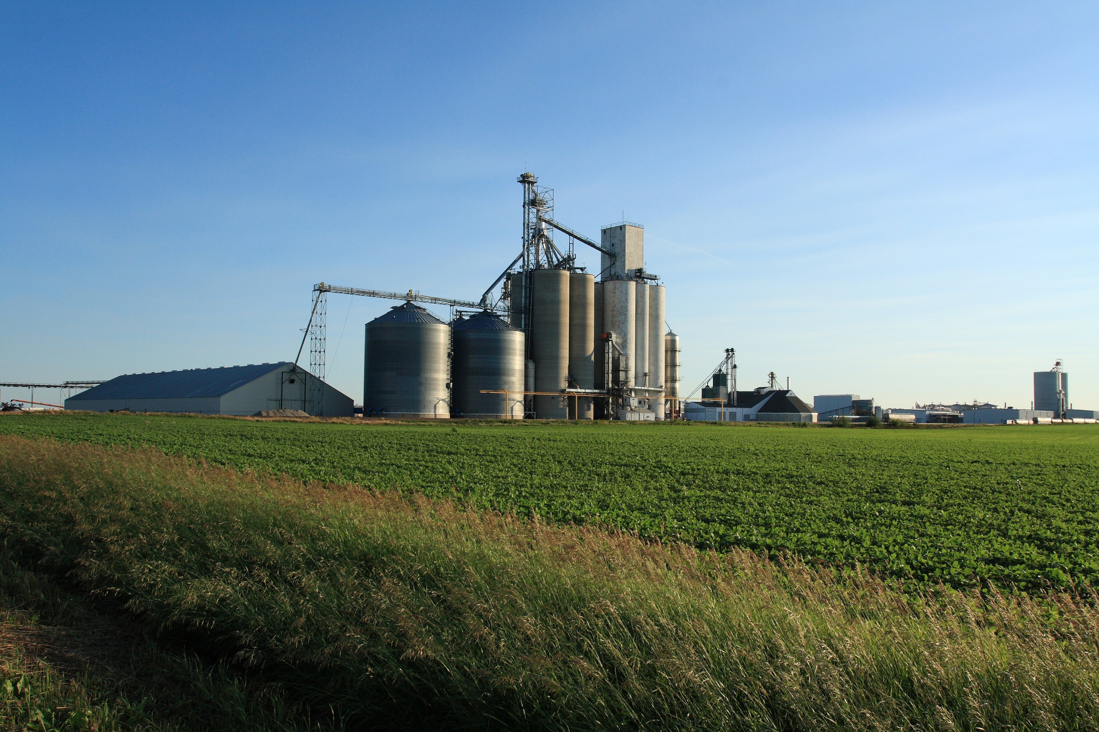 An ethanol plant in Iowa with a soybean field in the foreground