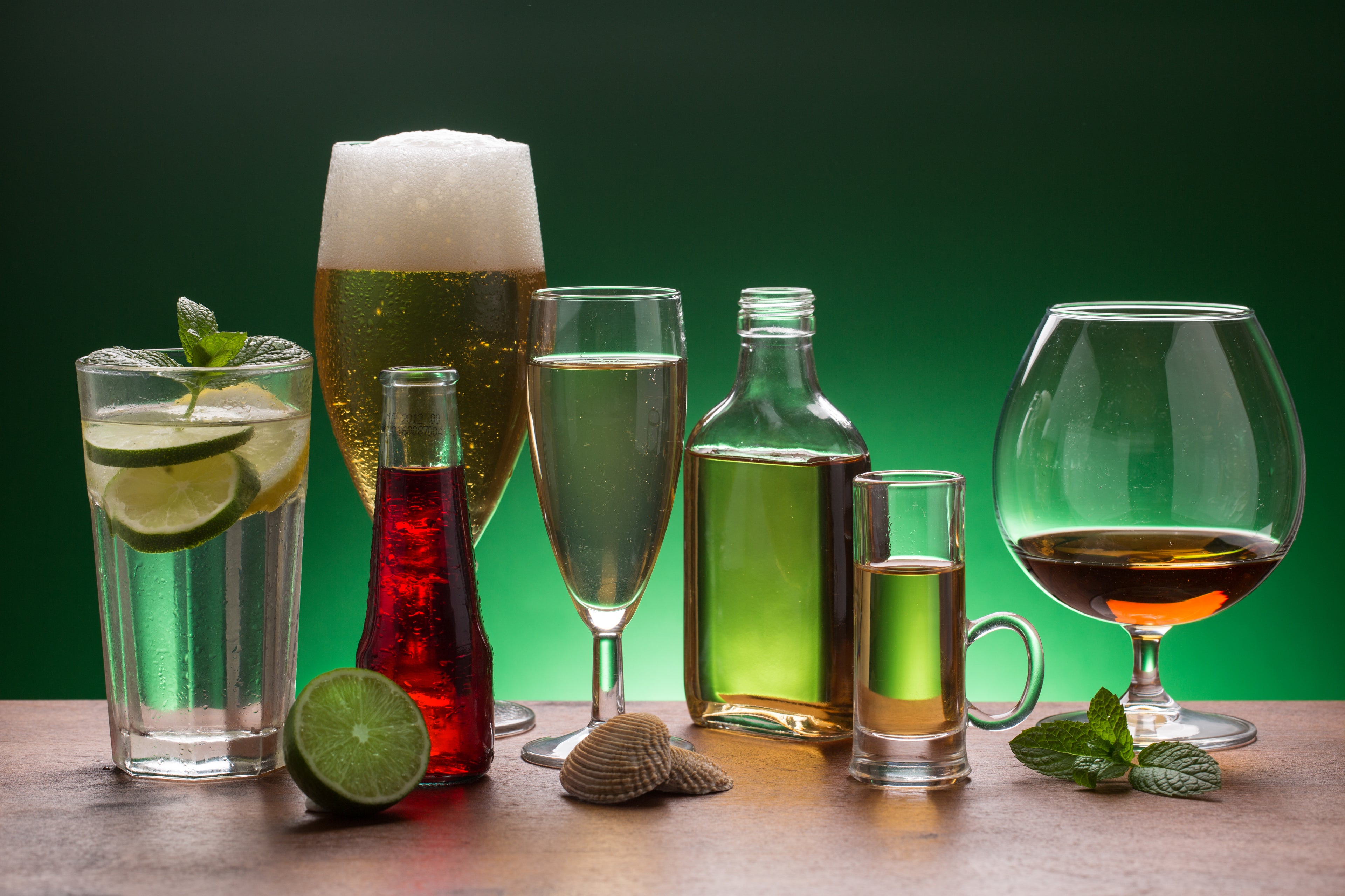 Variety of alcoholic beverages on green background
